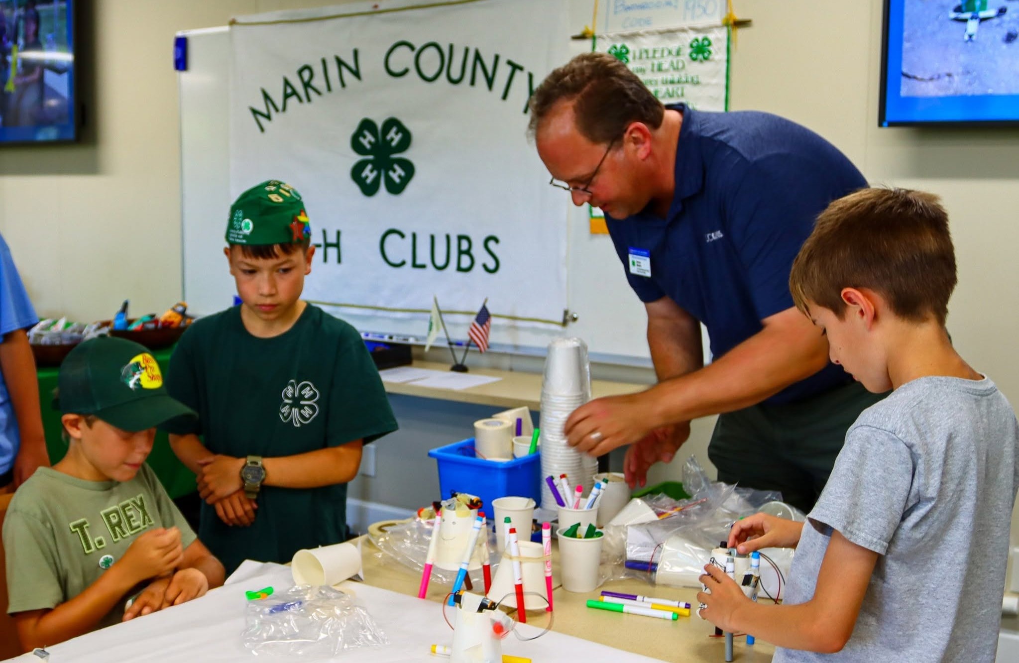 A man and three boys work at a table during a 4-H open house.
