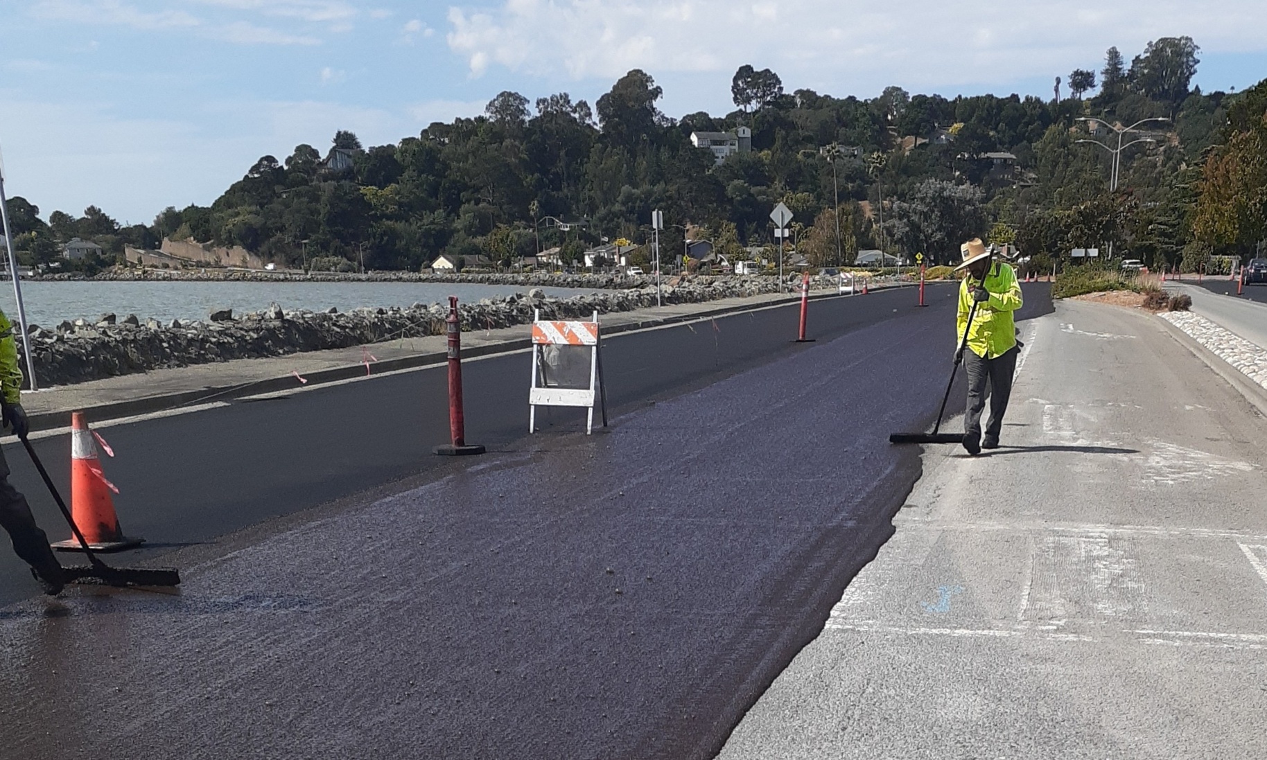 A worker in a hardhat inspects new pavement on a roads project.