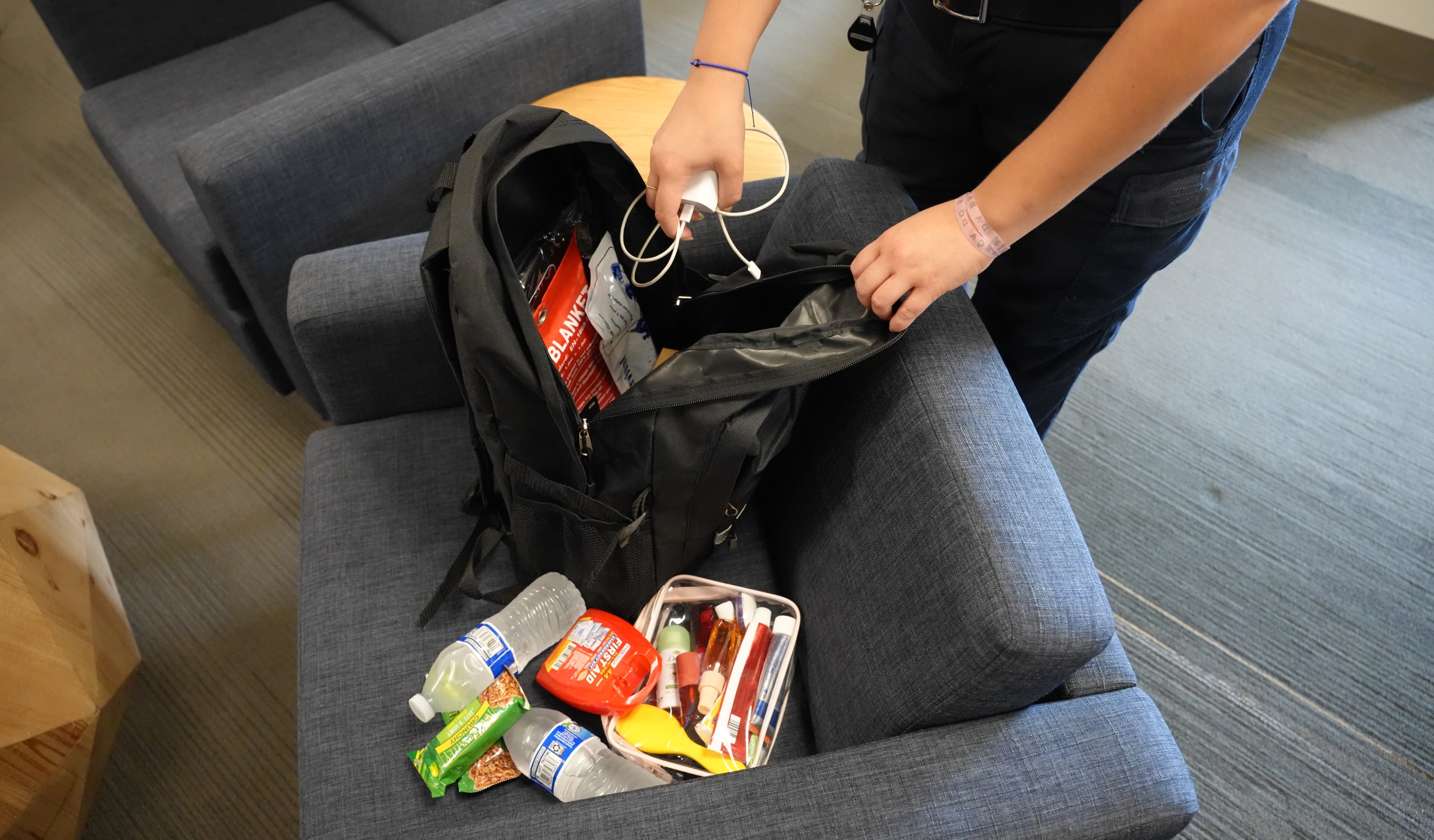 A person's hands reach down toward items that will be in an emergency "go bag."