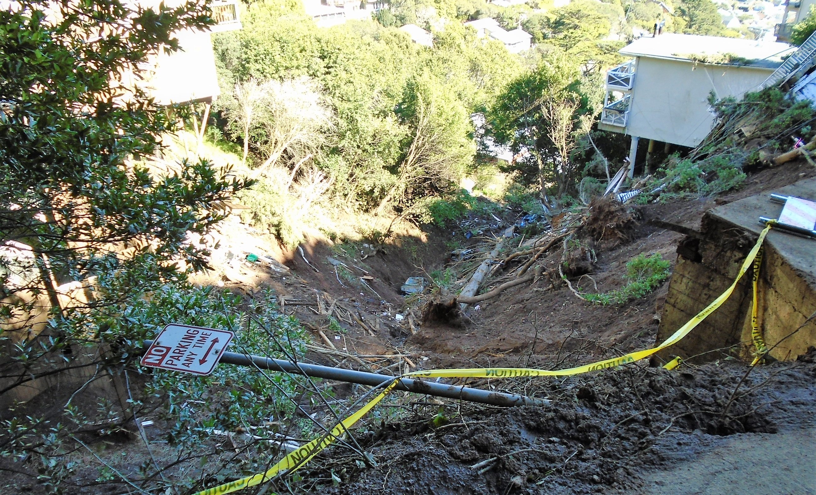 Caution tape on the ground next to a mudslide that took out a home in Sausalito during a past storm.