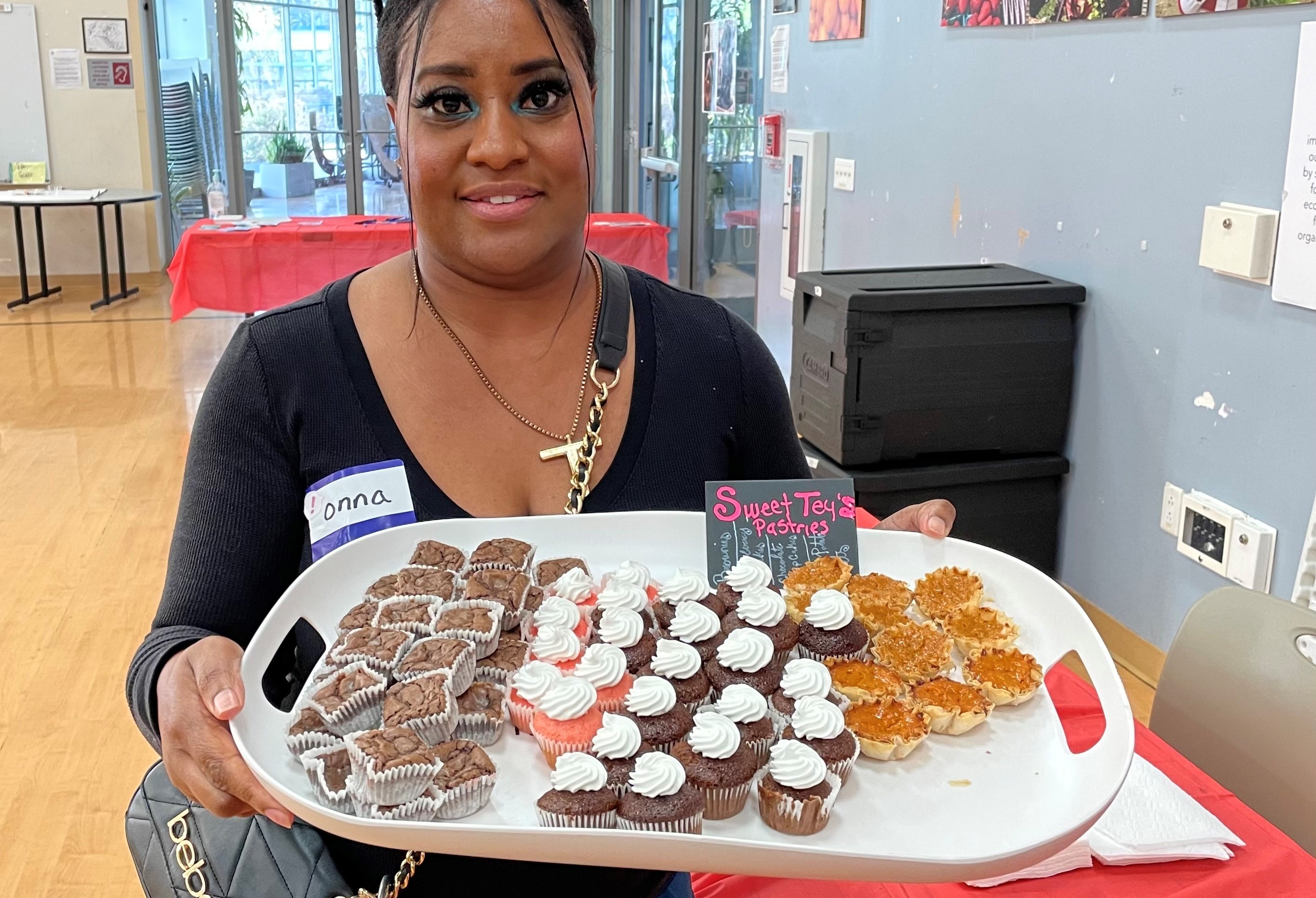 A woman holds up a tray of homemade pastries.