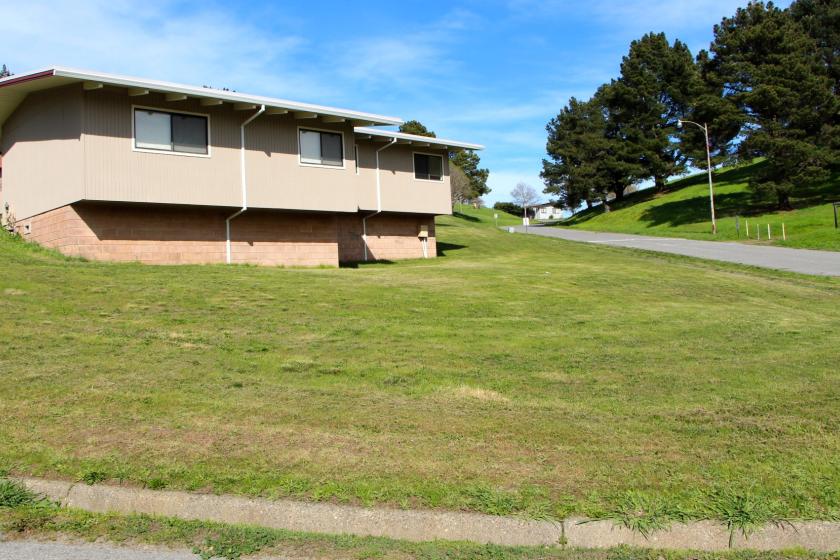 An old building at the former seminary property and an adjacent grassy hillside.