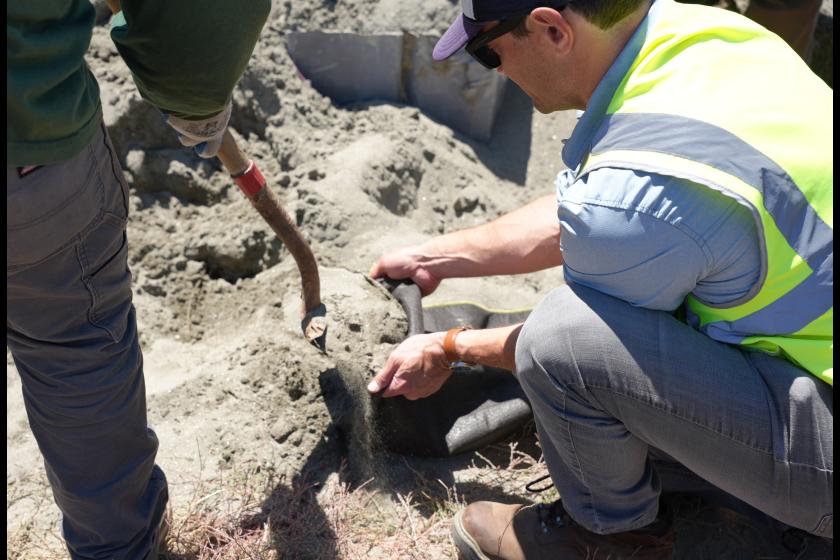 A man crouches down to make a sandbag.