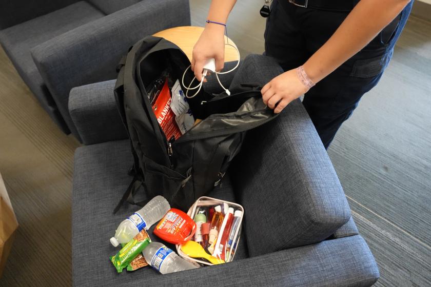 A person's hands reach down toward items that will be in an emergency "go bag."