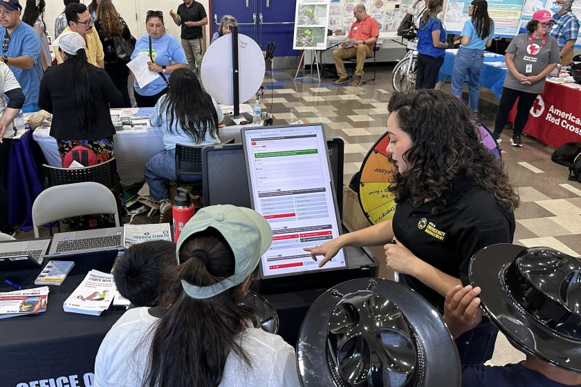 A female Fire Department representative speaks to a group of kids about emergency preparedness during a fair.