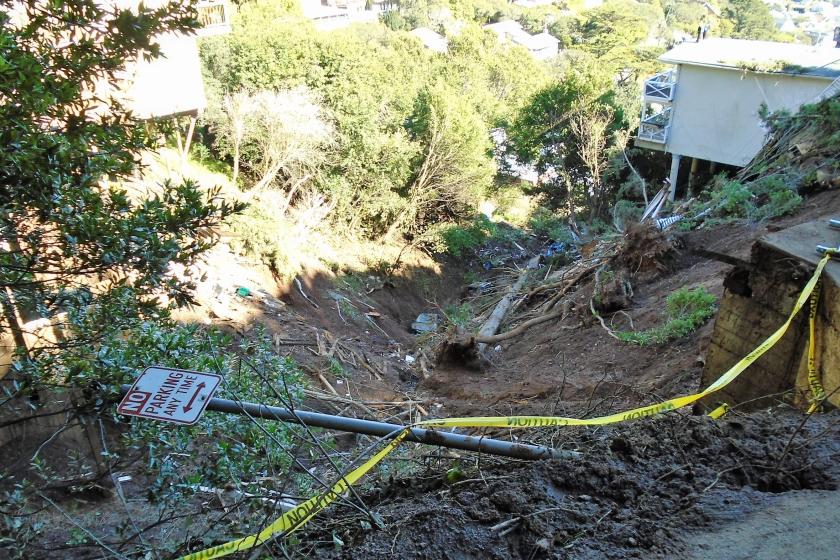 Caution tape on the ground next to a mudslide that took out a home in Sausalito during a past storm.