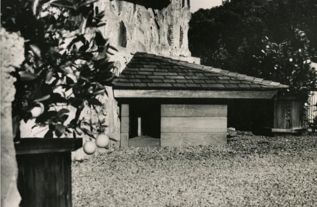 Black and white photo of a Frank Lloyd Wright designed doghouse in a yard.