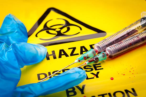 Disposable glove and bloody syringes lying on top of a hazard bag.