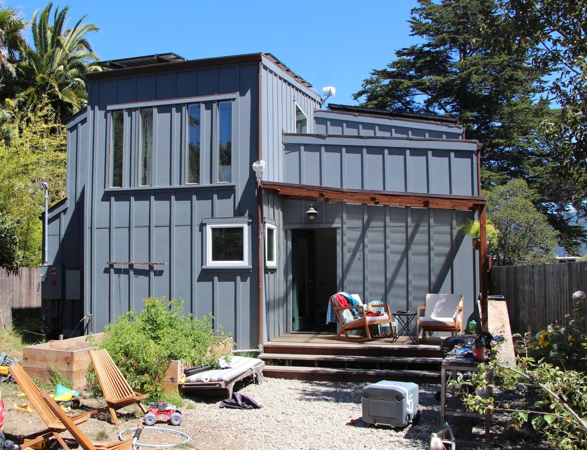 Grey two story home with a front porch with two chairs.