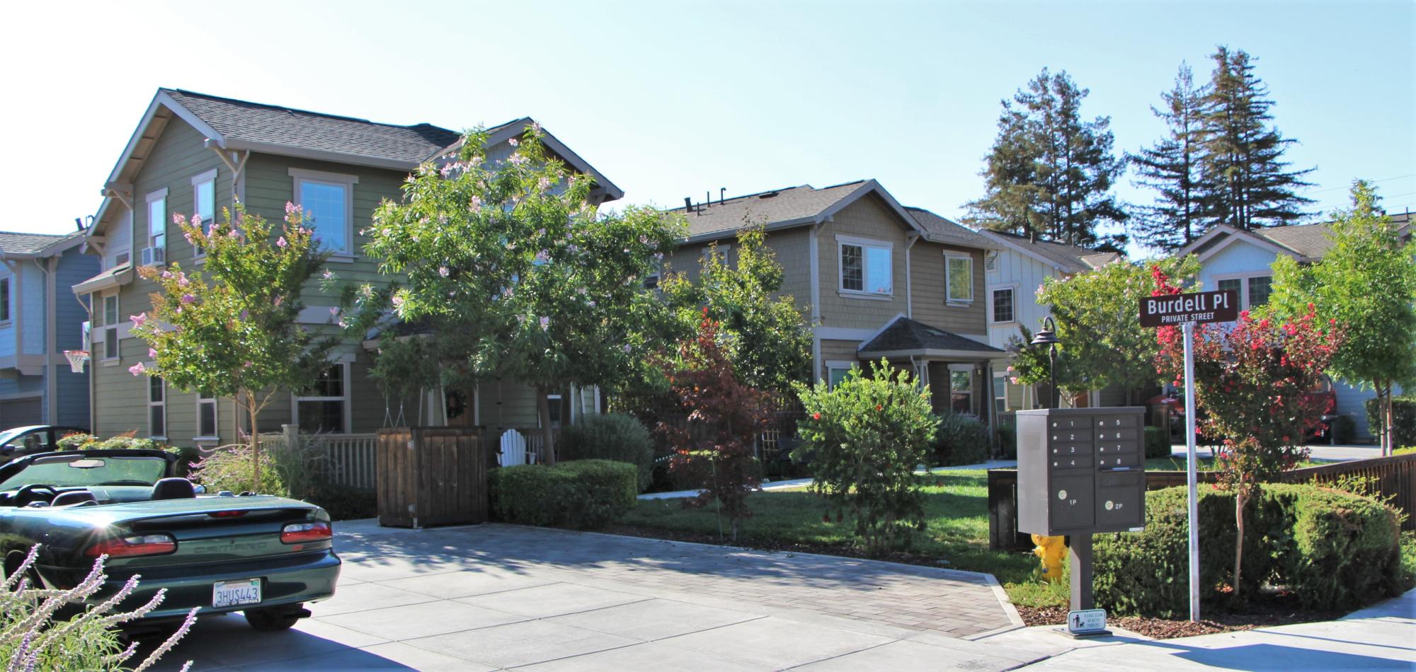 Several two story single family homes with driveways and front yards lined with trees and shrubbery.