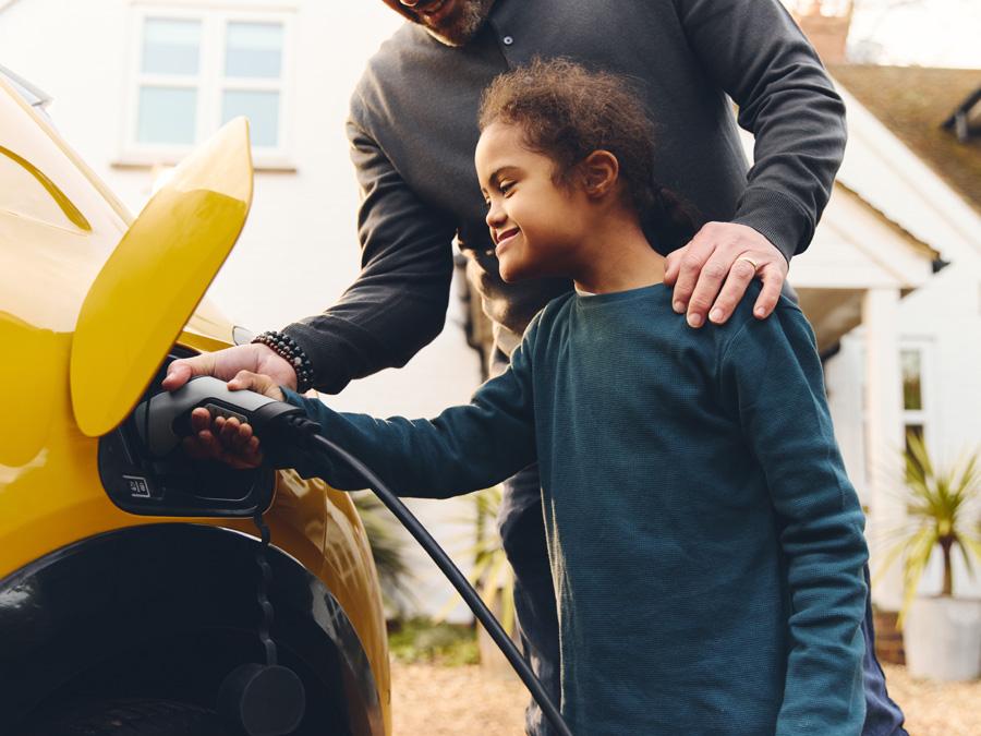 A man shows a child how to charge a car.