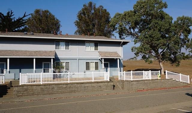 Two story townhome lined with a white fence.