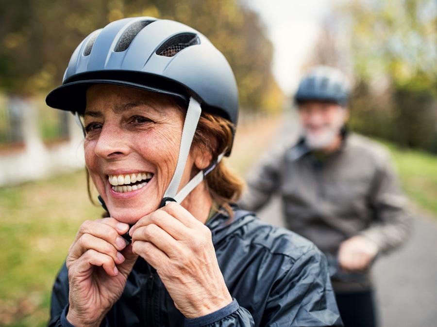 A woman puts on her bike helmet.