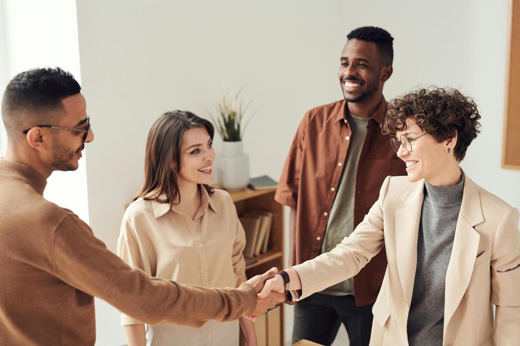 Four people smiling at each other, with two shaking hands.