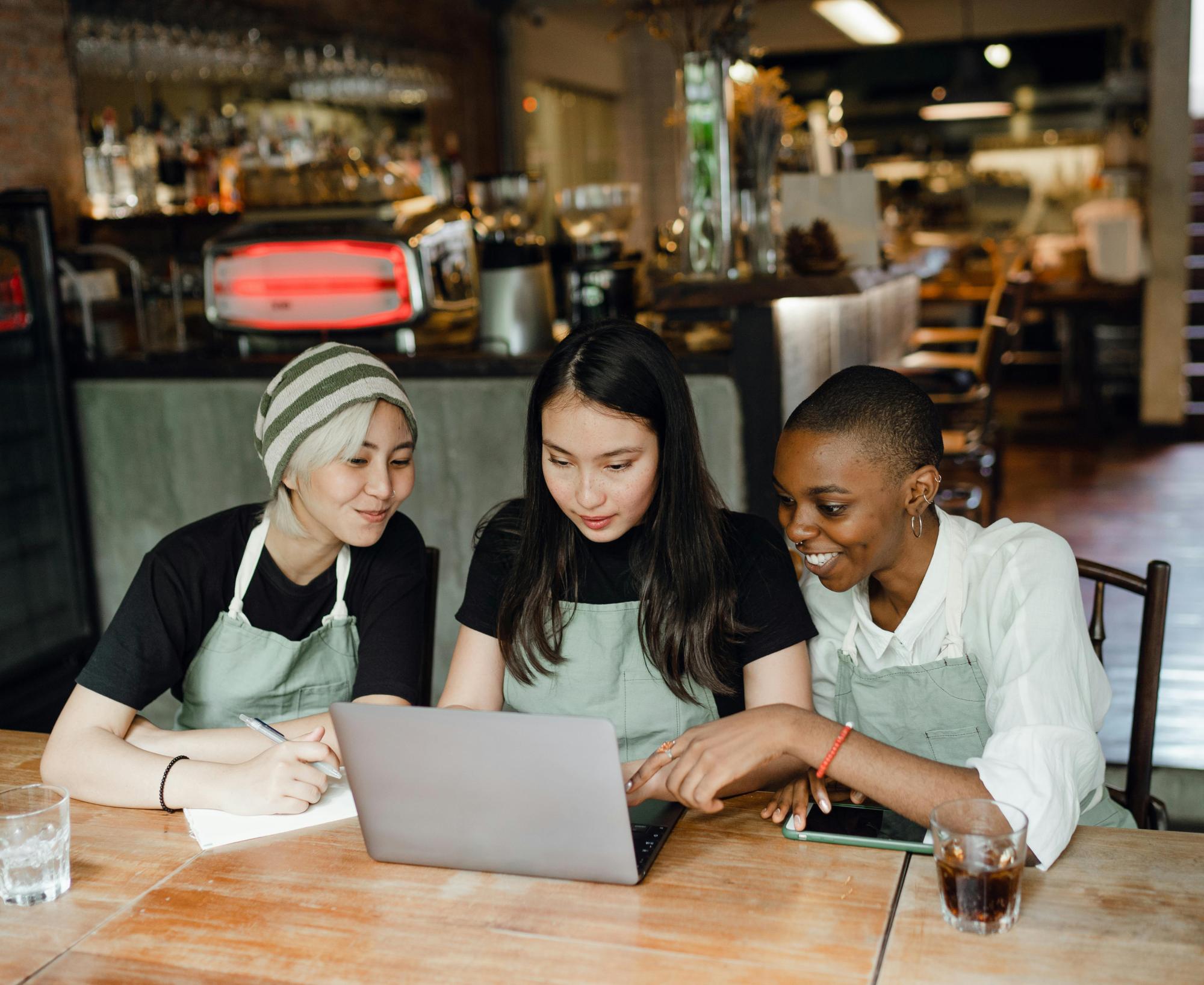 People conducting employee training at a café, gathered around a computer.