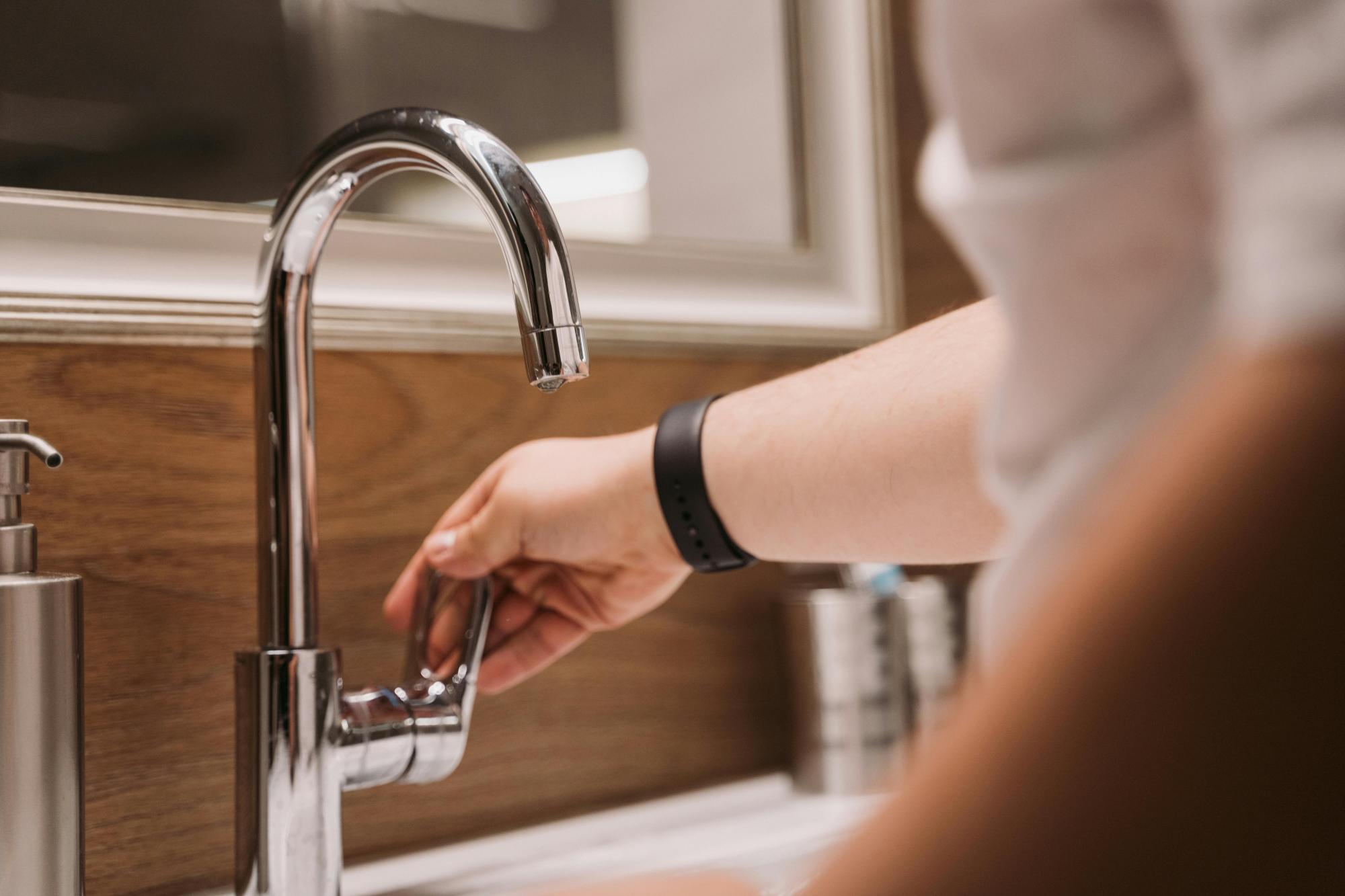 Person inspecting water flow from a faucet.