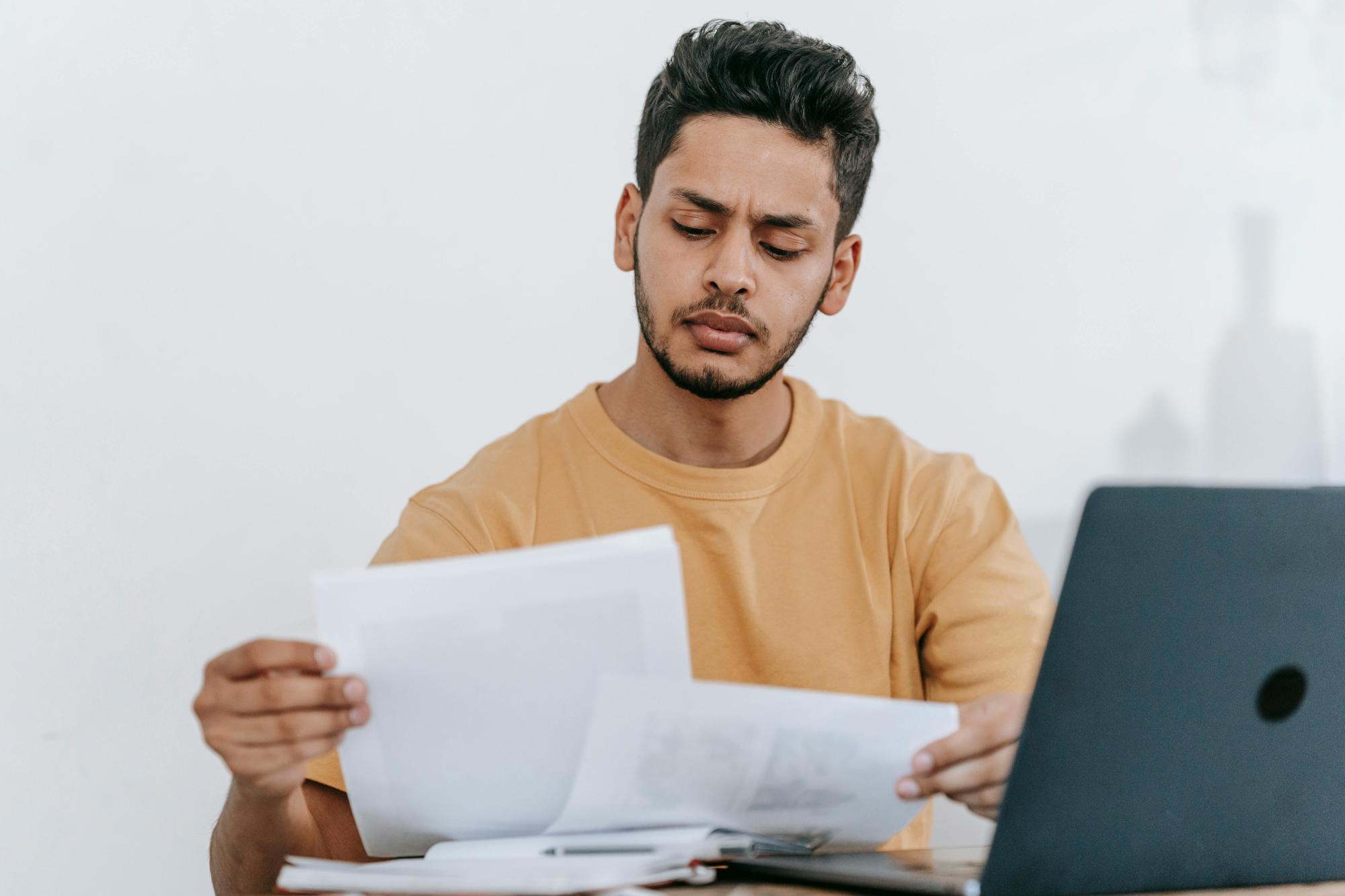 Person organizing papers and working on a business plan, using a computer.