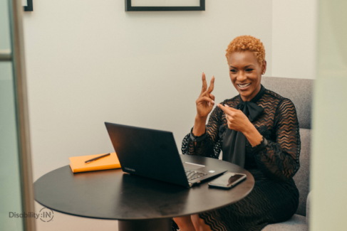Woman facing open laptop while using sign language to communicate.