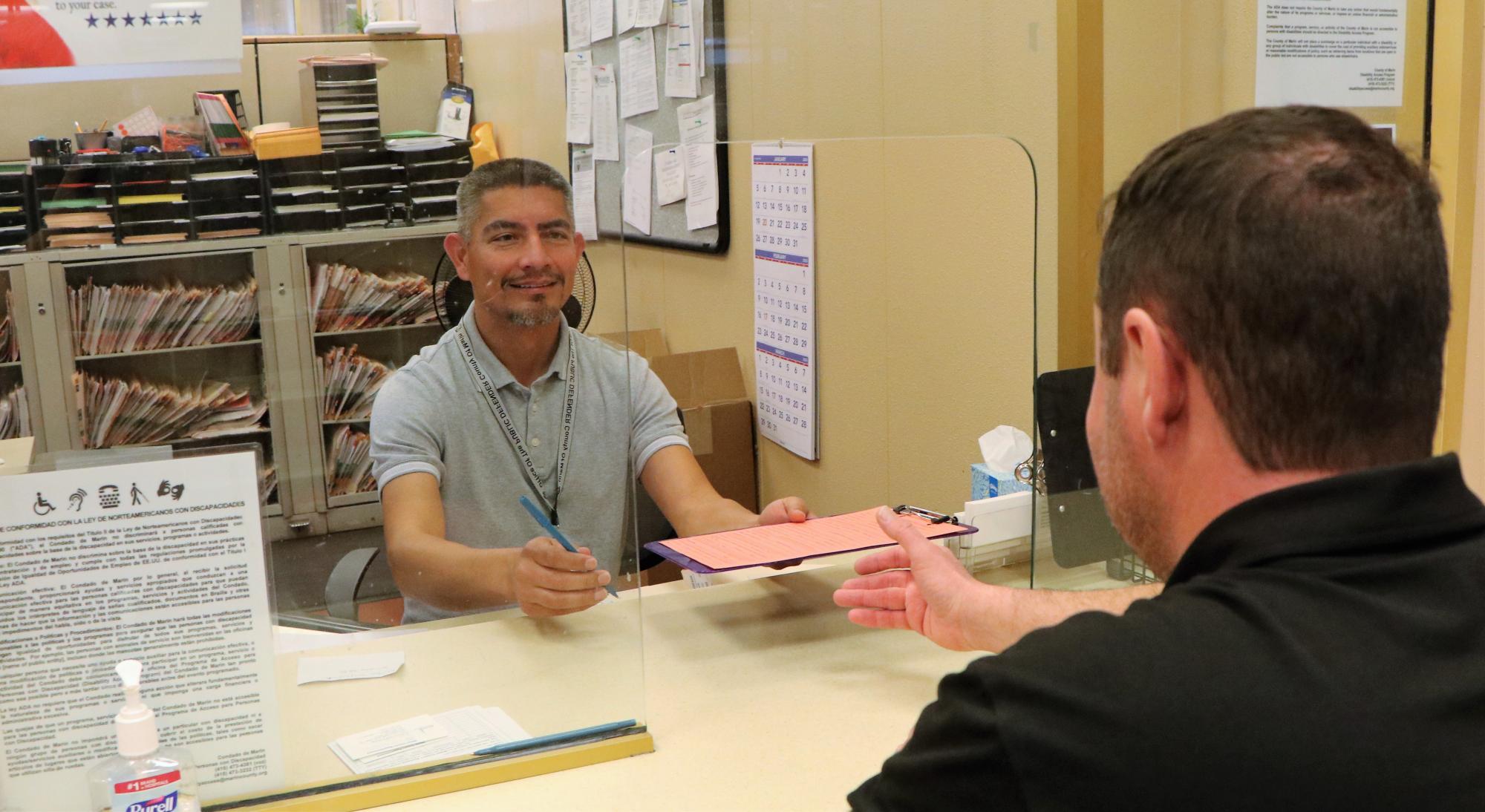 Staff member working at the front desk assisting a person from the community