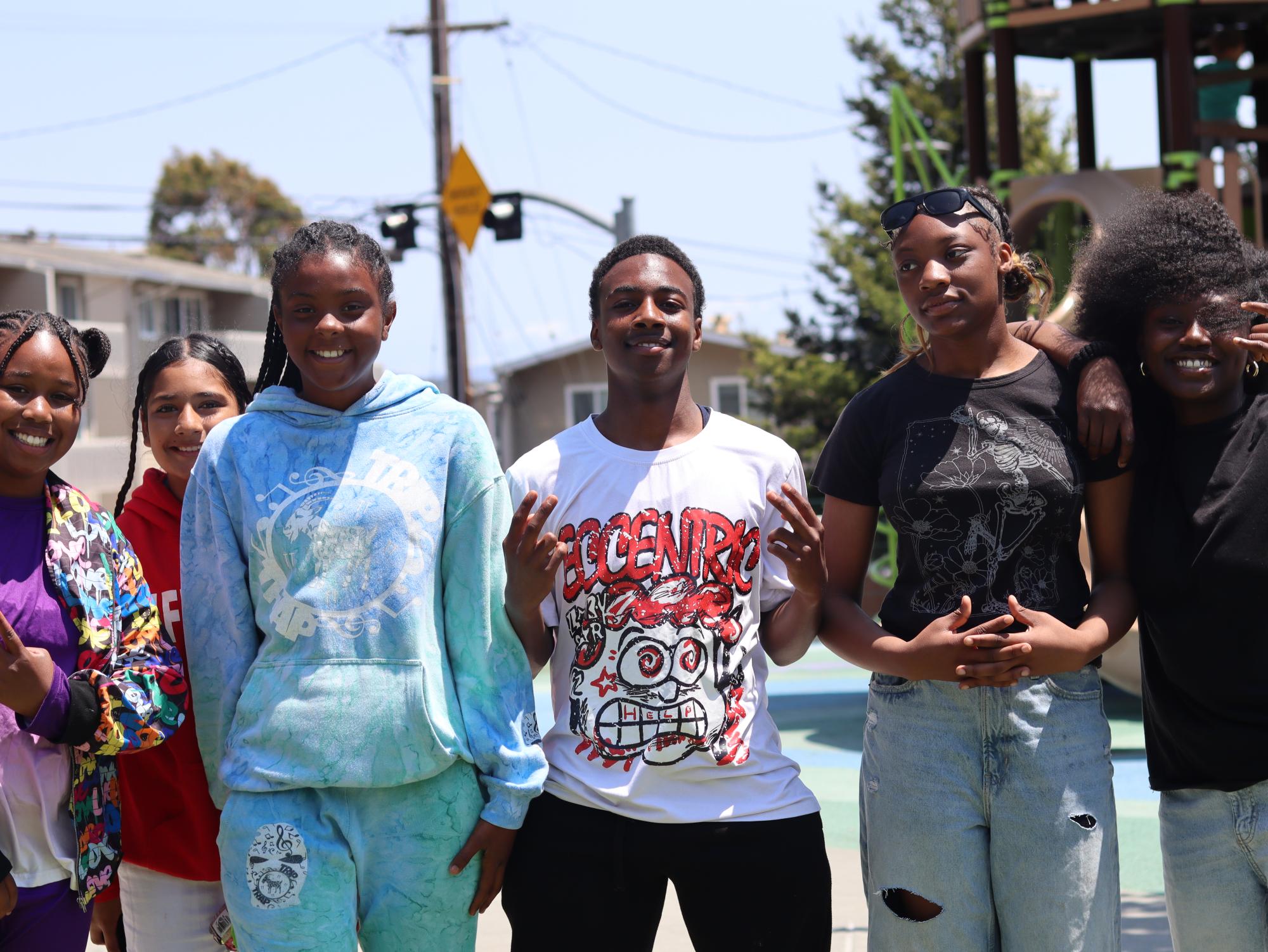 A group of young people standing together outdoors near a playground.