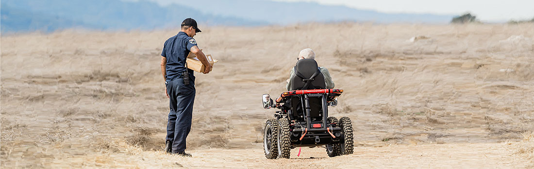 Parks staff walking alongside man in a TerrainHopper mobility device