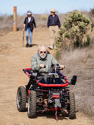Man driving TerrainHopper with two people walking behind him
